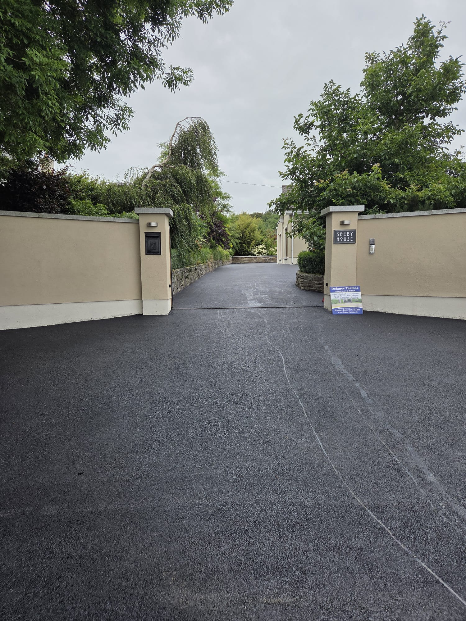 Finished tarmac driveway at a gated country entrance between rendered pillars, laid by Delaney Tarmac