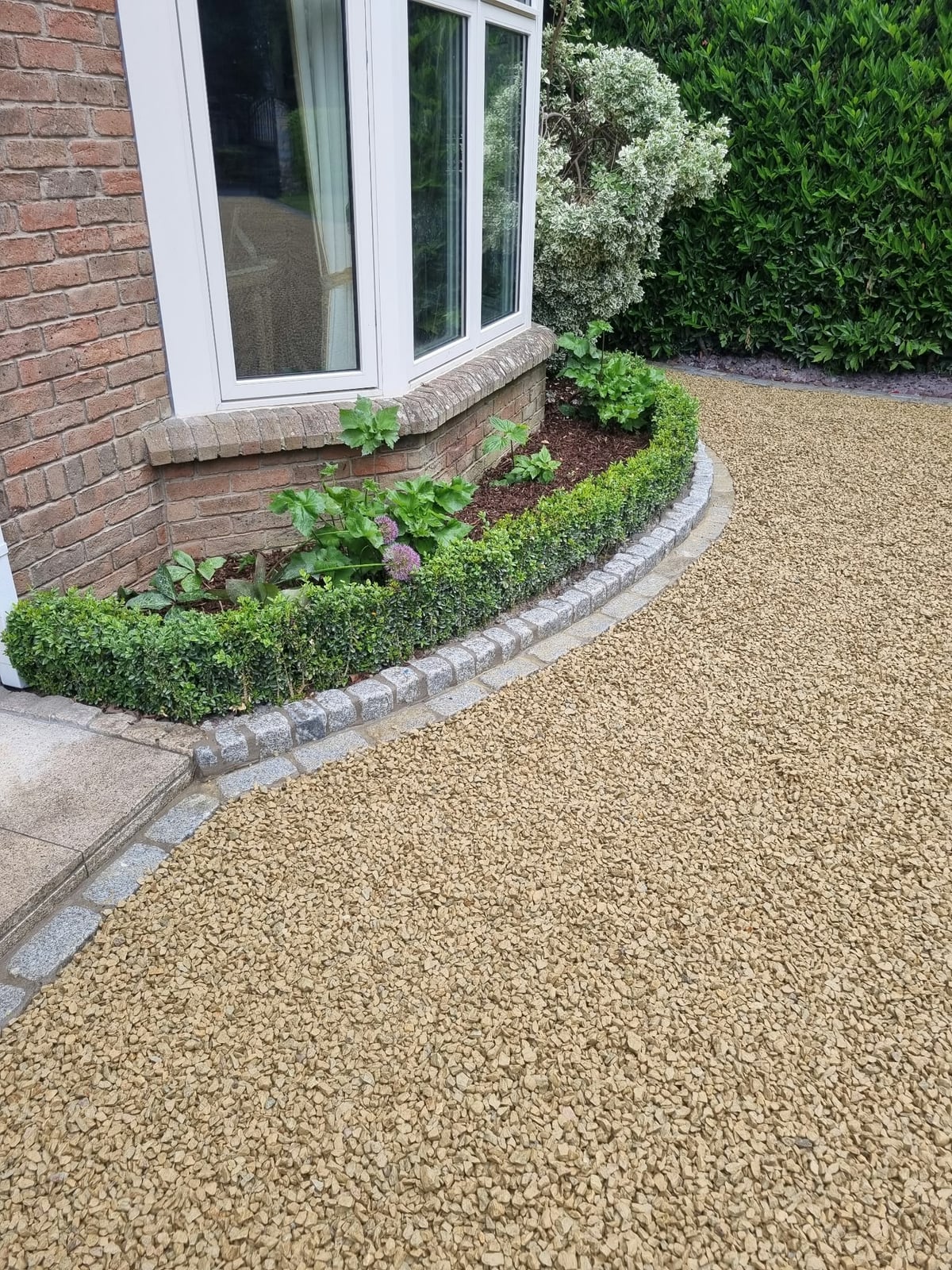 Granite cobble kerb curving round a planting bed at the house, with the gravel driveway