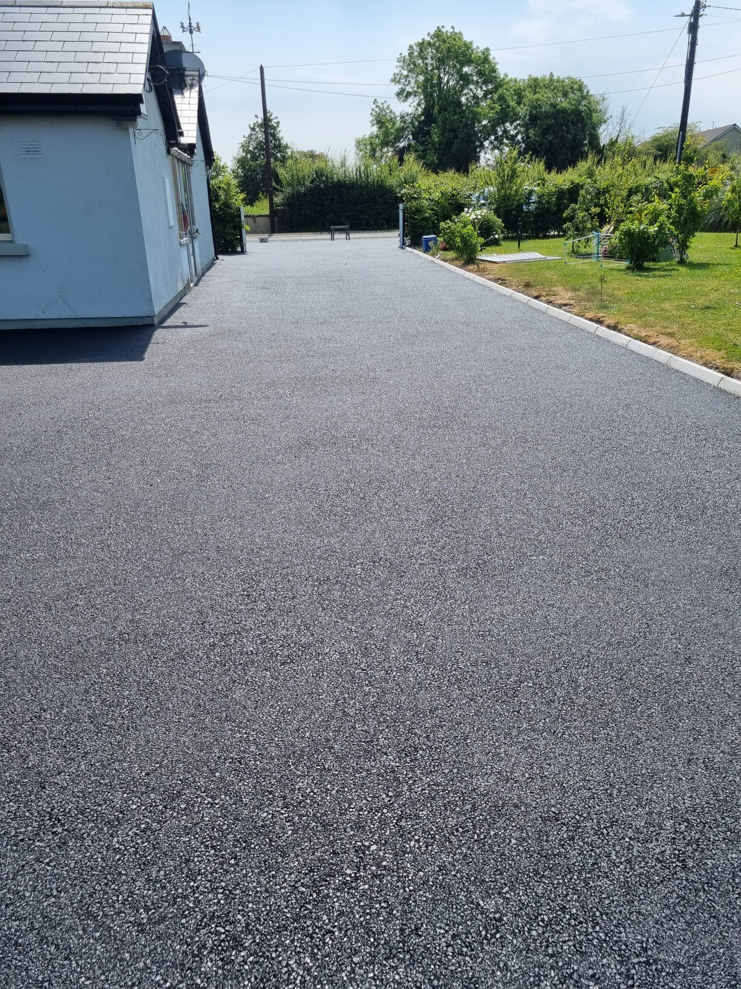 Tarmac driveway at an older bungalow with mature hedge boundary