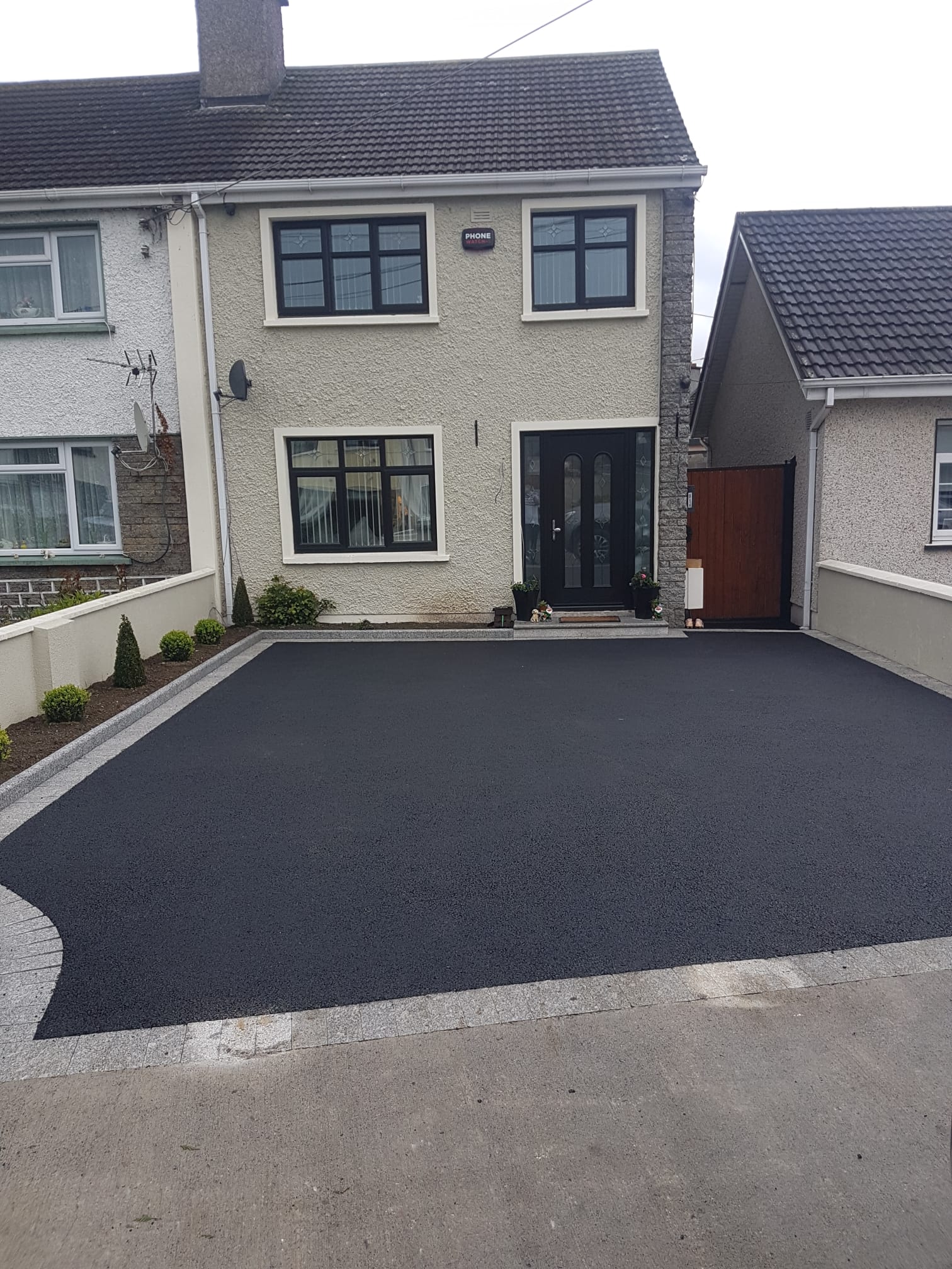 Tarmac driveway at a cream pebbledash semi-detached home