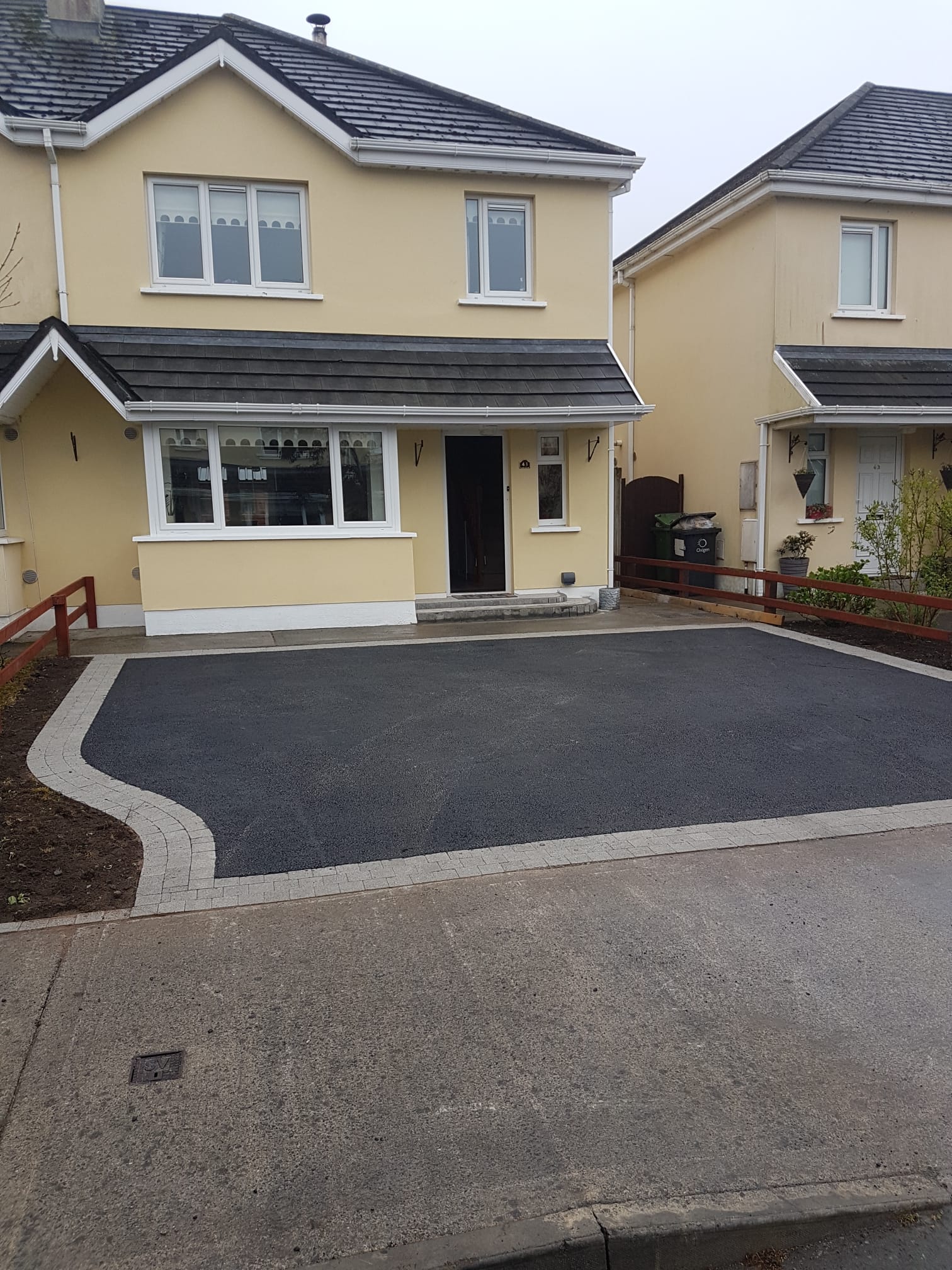 Tarmac driveway at a cream semi-detached suburban home with granite cobble border