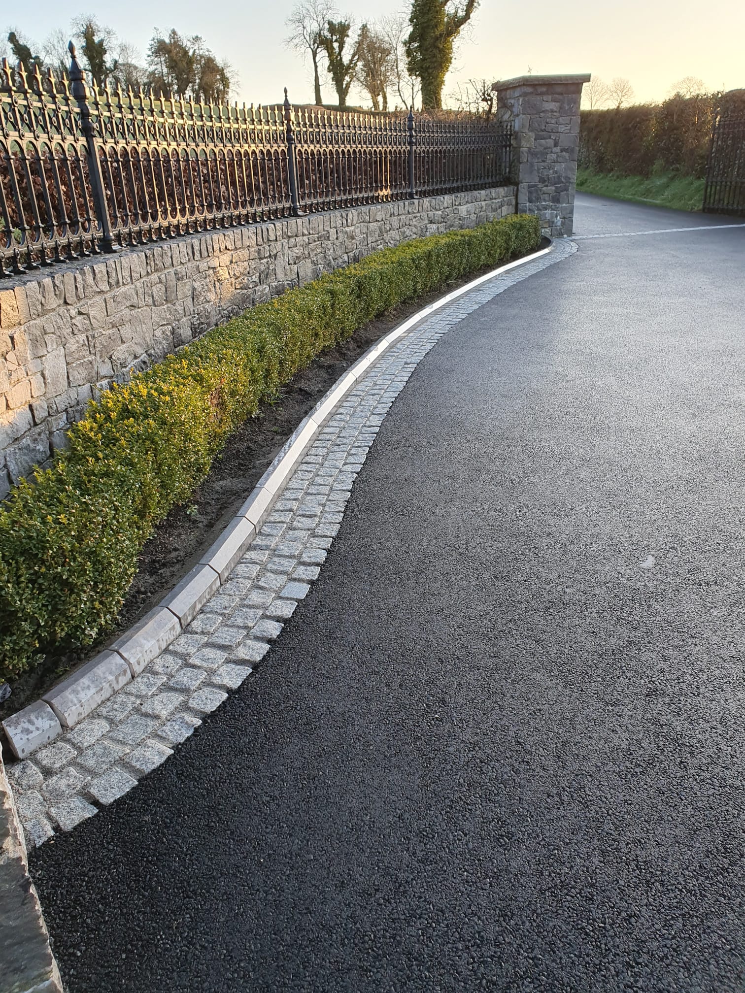 Curving tarmacadam driveway with granite cobble border, an example of how surface choices can be combined on the same property
