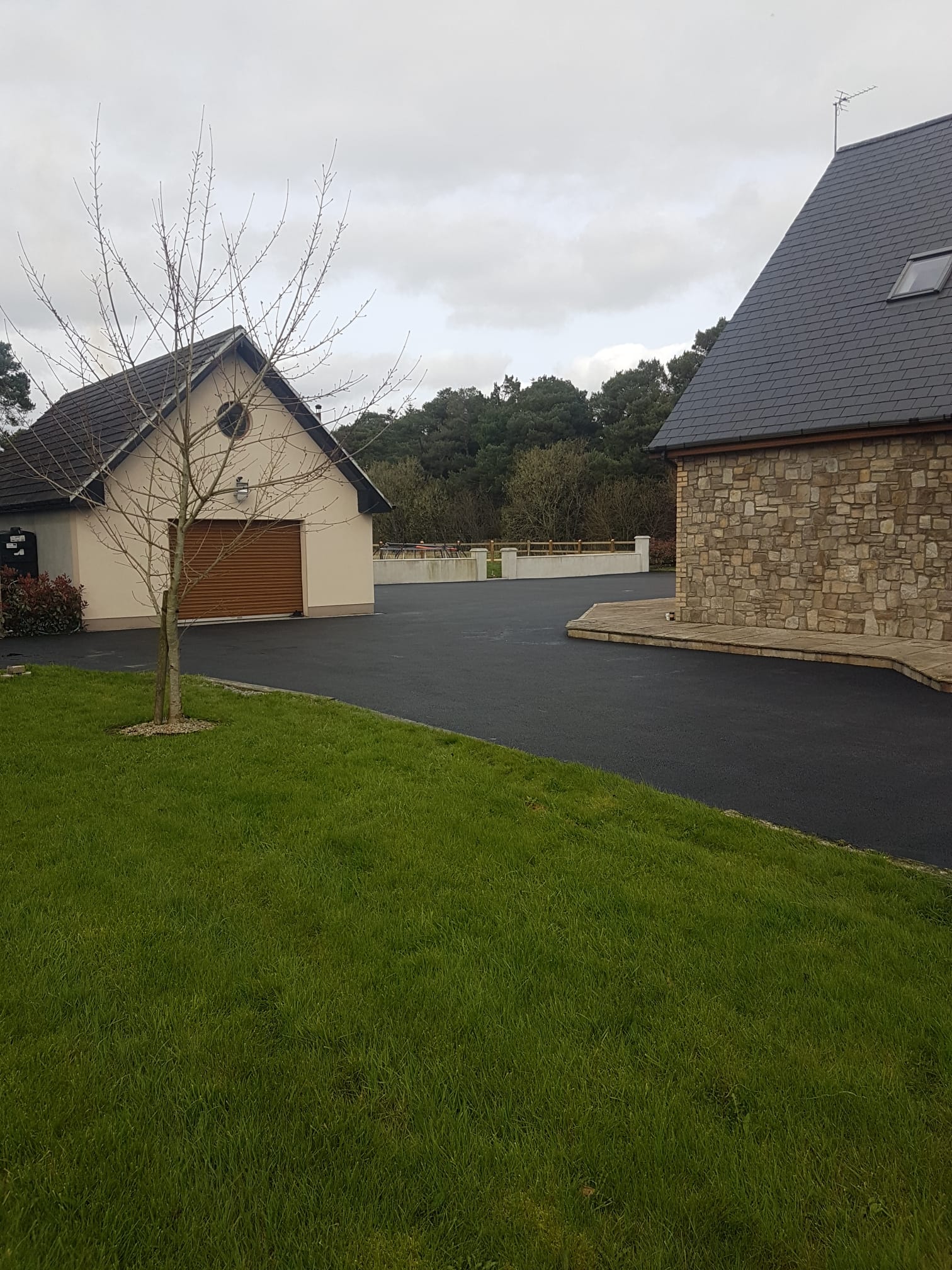 Tarmac driveway at a modern home with stone-clad garage side wall