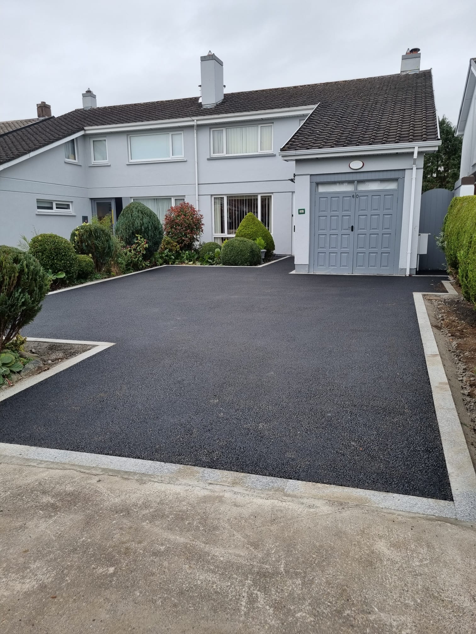 Tarmac driveway at a semi-detached suburban home with grey front doors