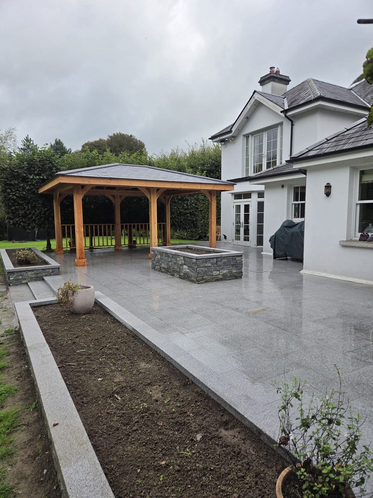 Granite patio under the cedar gazebo looking out over the lawn and raised beds