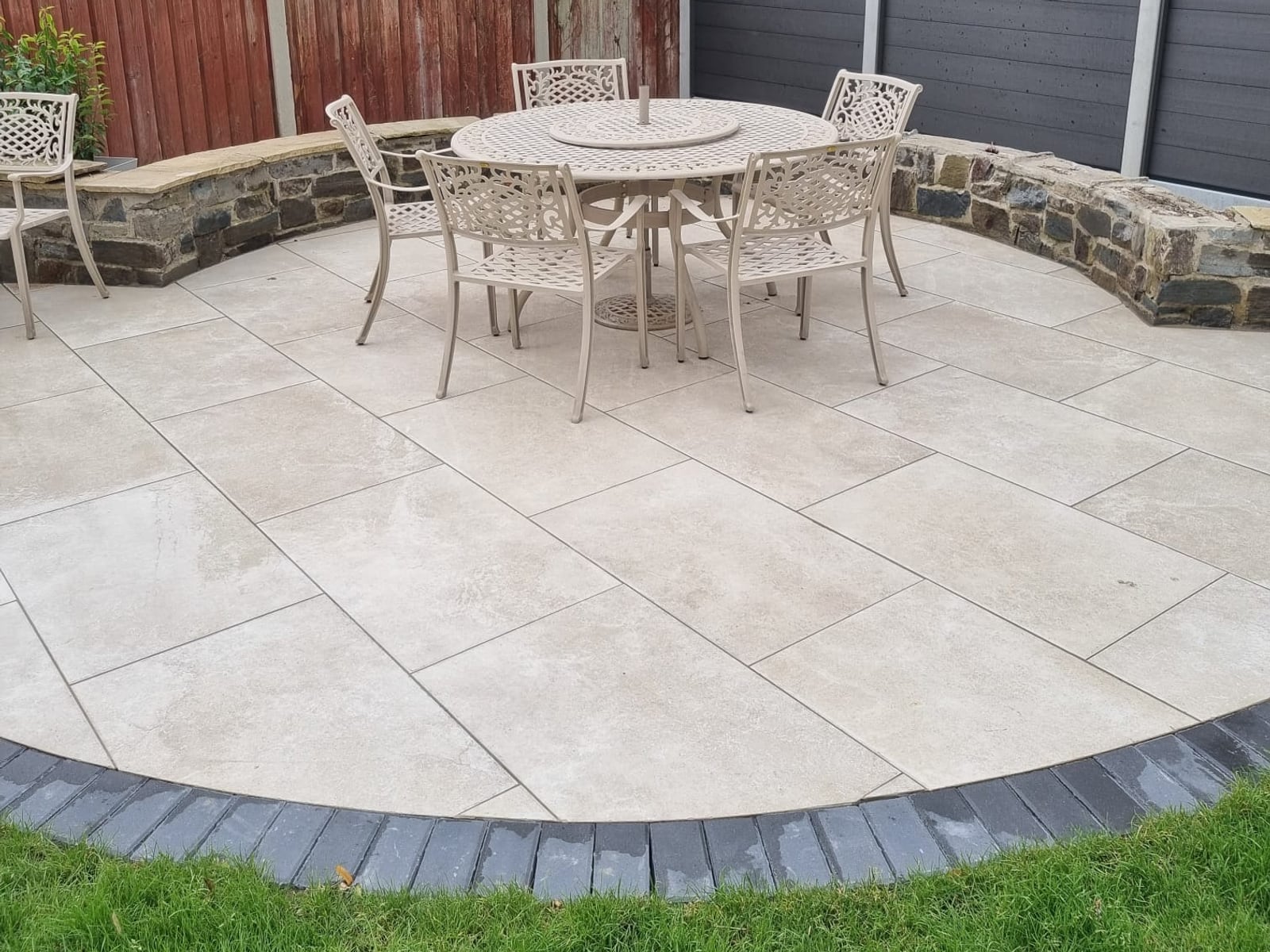 Round paved seating area with a dark sett border and a stone-faced seating wall