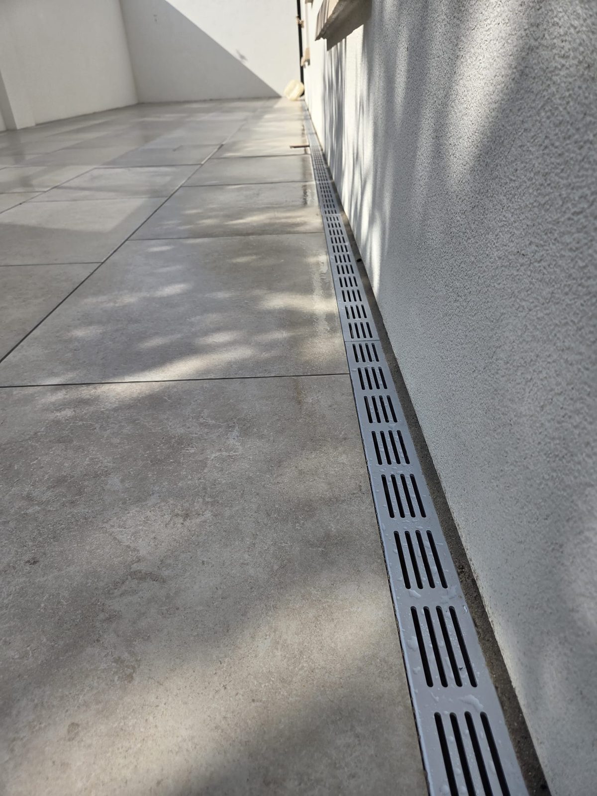 Grey porcelain patio with a channel drain running along the wall