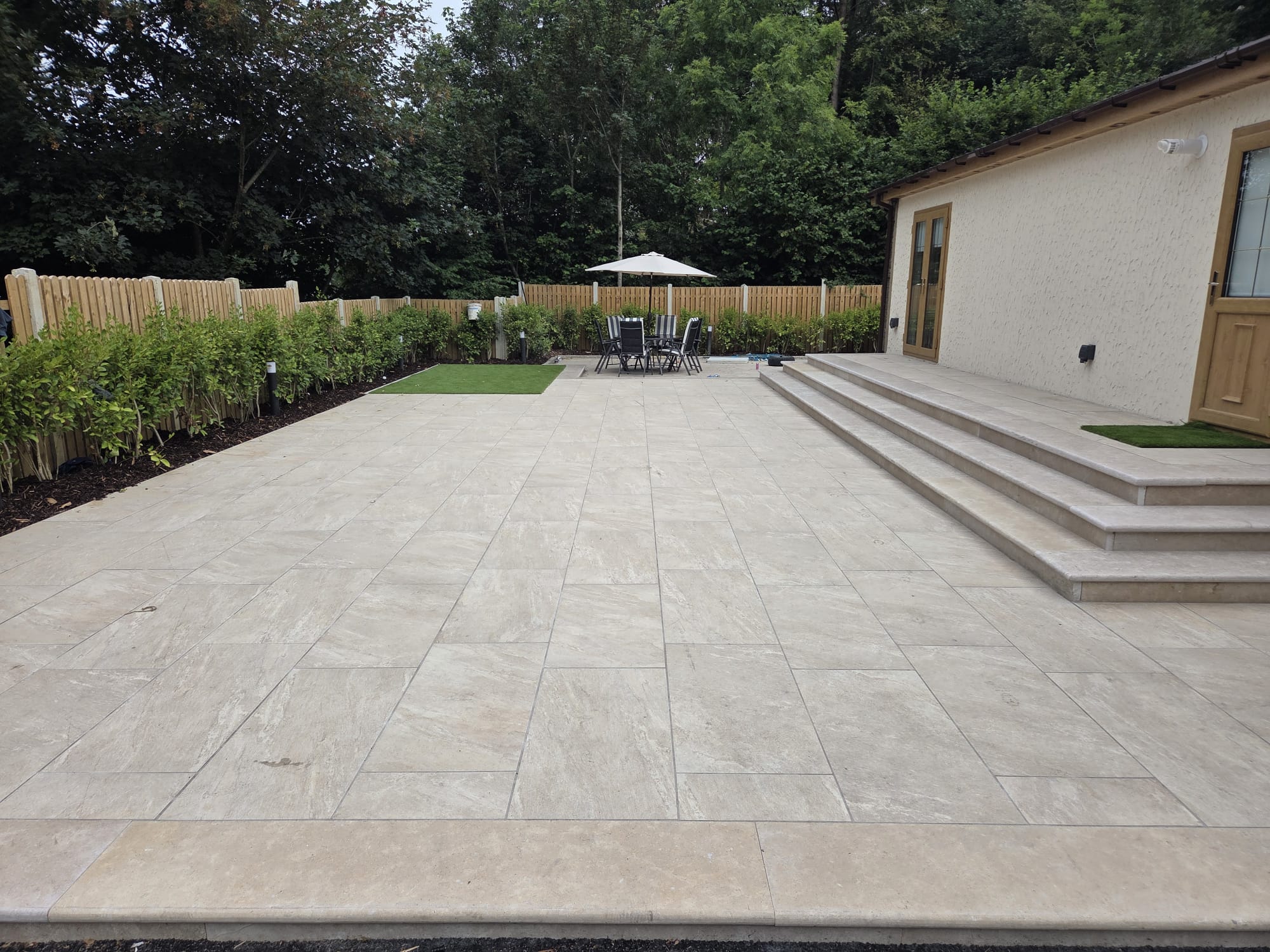 Cream porcelain patio with steps up to a rendered bungalow