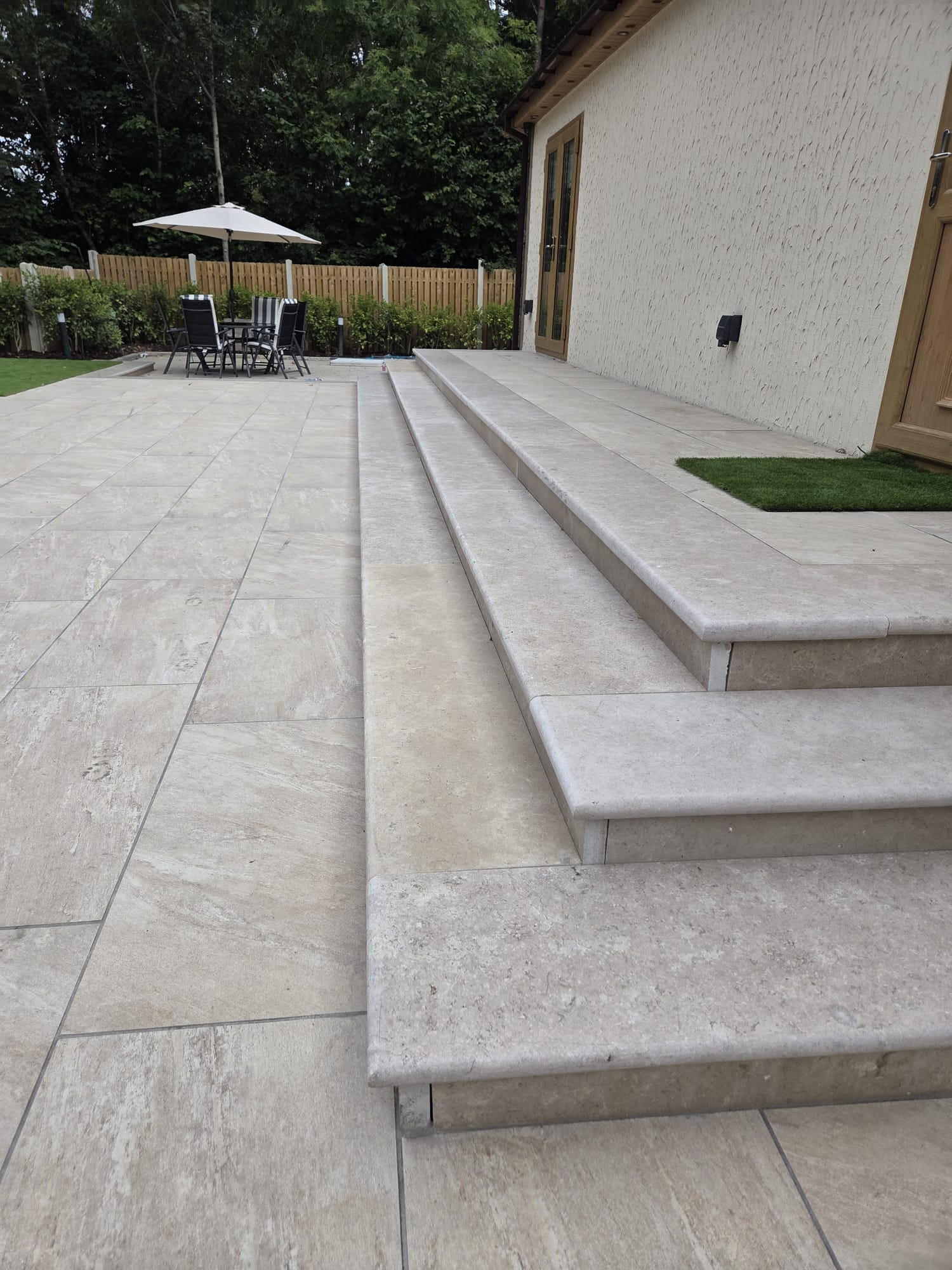 Cream travertine-effect porcelain patio with wide steps and a seating area