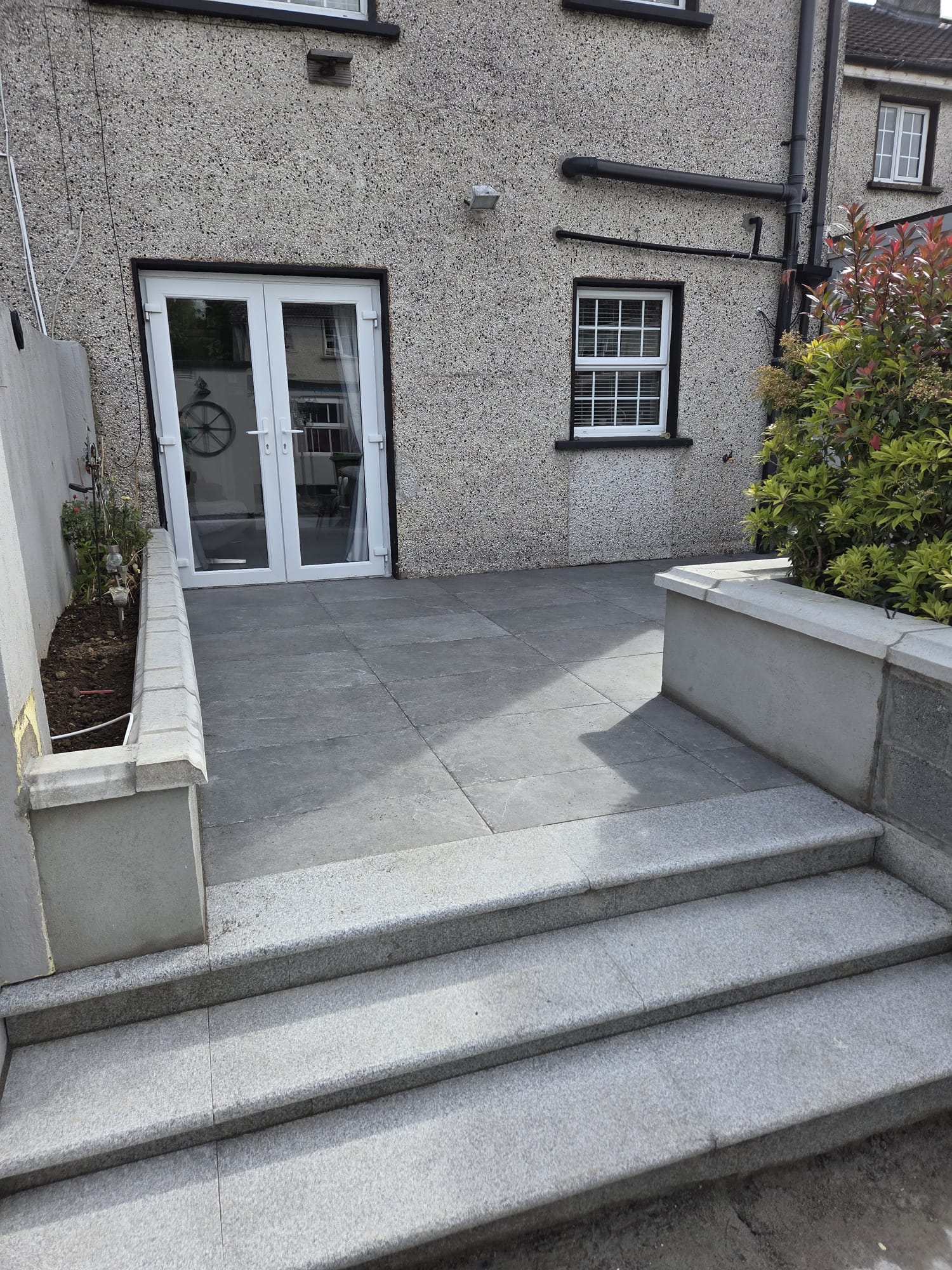 Porcelain patio with granite steps at a pebbledash house