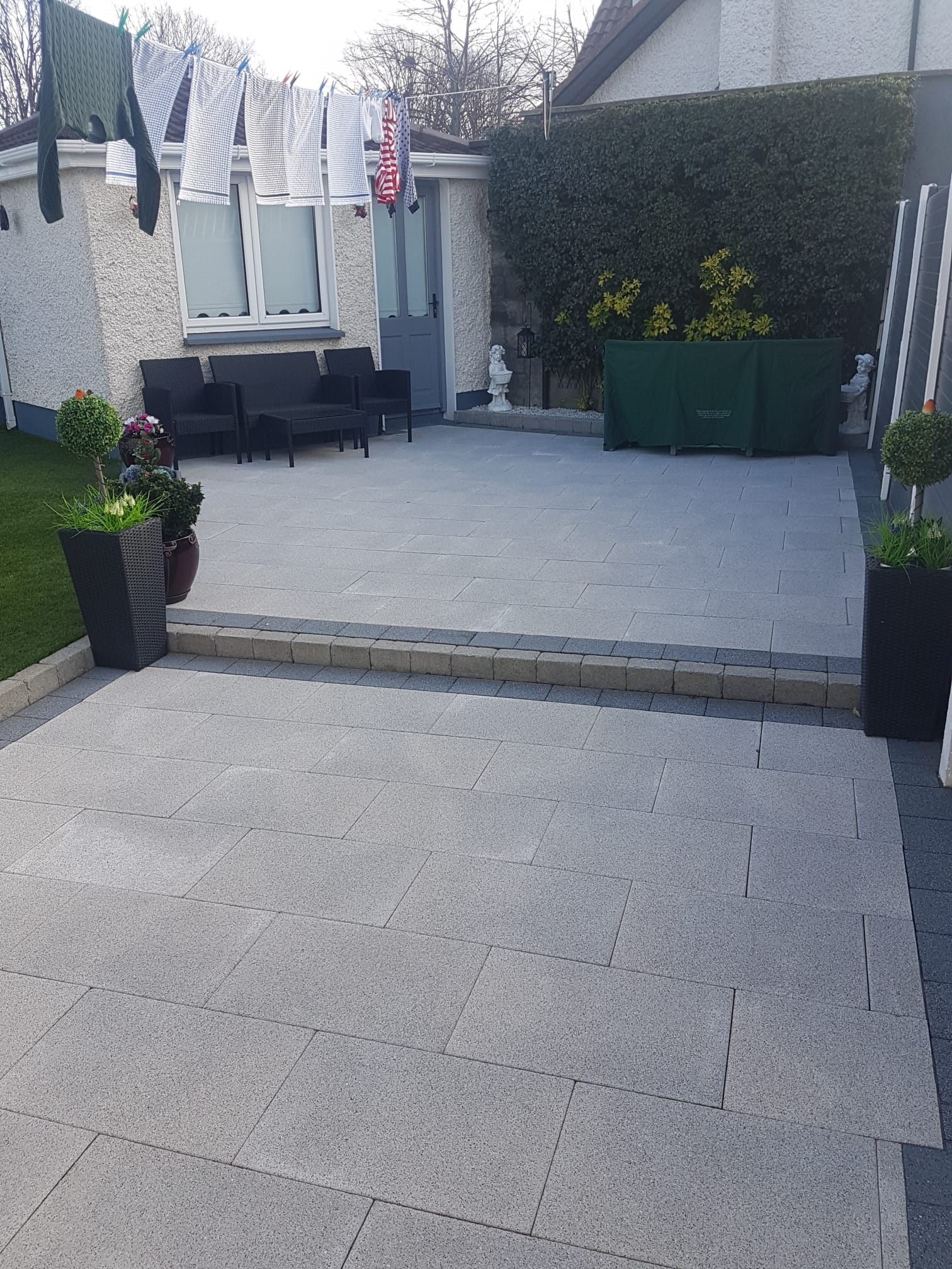 Porcelain patio with rattan furniture and granite step risers next to a clothesline