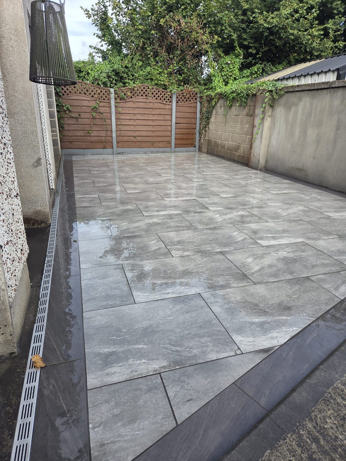 Grey porcelain side return with a channel drain along the wall, laid by Delaney Tarmac