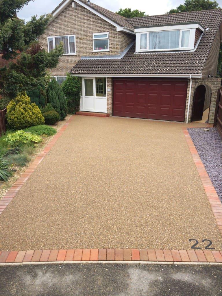 Golden resin bound driveway with brick paver border at a large family home