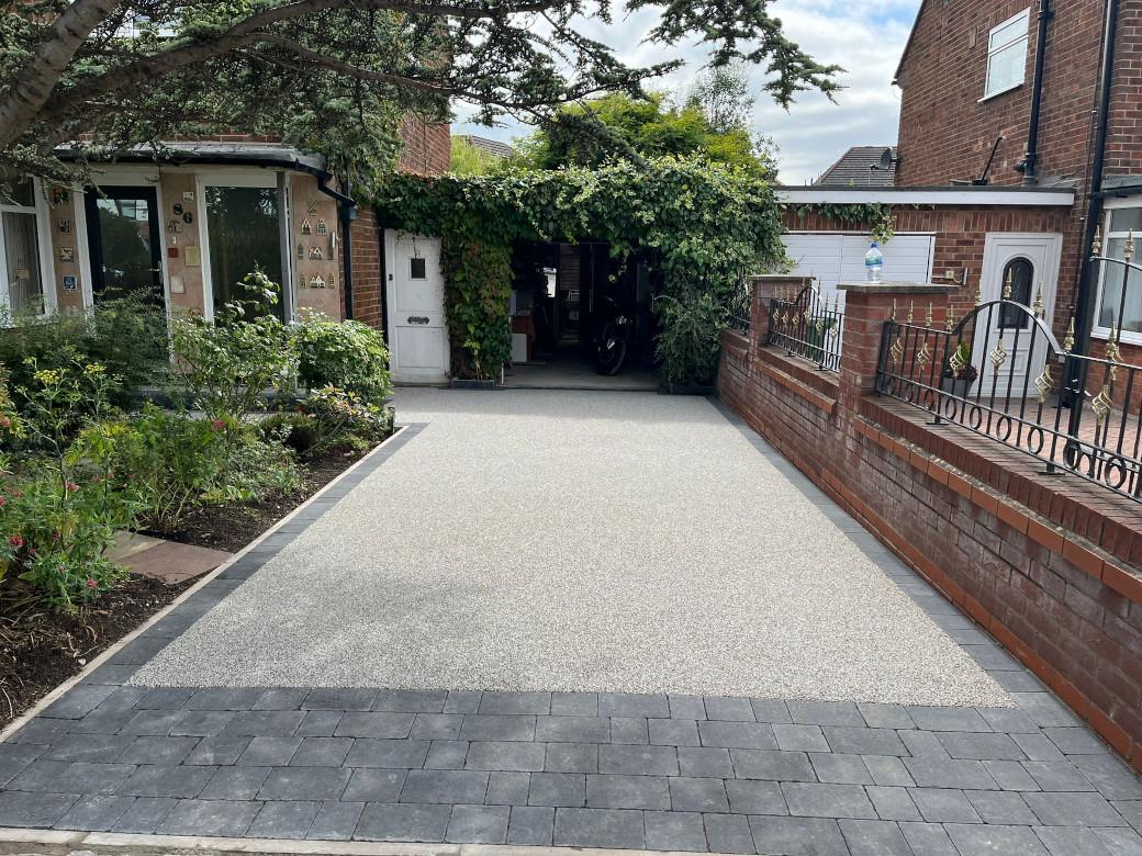 Cream resin bound driveway with charcoal block border and front garden planting
