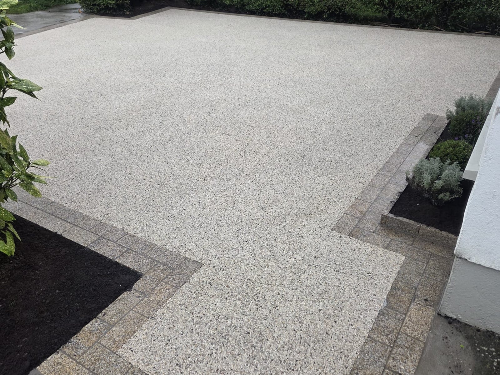 Resin-bound driveway with a granite sett border and planting beds behind a granite kerb, laid by Delaney Tarmac